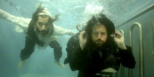 This undated photo provided by Channel 8 and Go2Films shows Ori Gruder, left, and rabbi Yisrael Aharon Itzkovitz swimming in their clothes in a ritual bath, which is created for publicity purpose for "Sacred Sperm," a film Gruder directed. The movie has been screened at festivals in Israel, London and California and continues in the coming weeks to other U.S. locations, including Atlanta on Feb. 15, 2015. Gruder created "Sacred Sperm," an hour-long documentary in which he tries to tackle the hard questions he can expect from his son. (AP Photo/Gliad Kavalerchik)